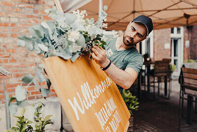 Florist dekoriert Willkommenstafel mit Blumen
