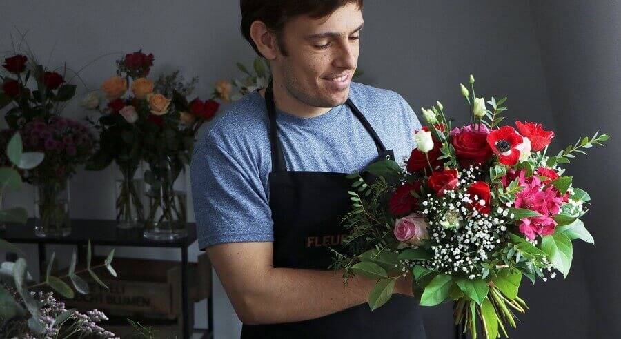 Florist, der einen Strauß in Rot-Pink bindet