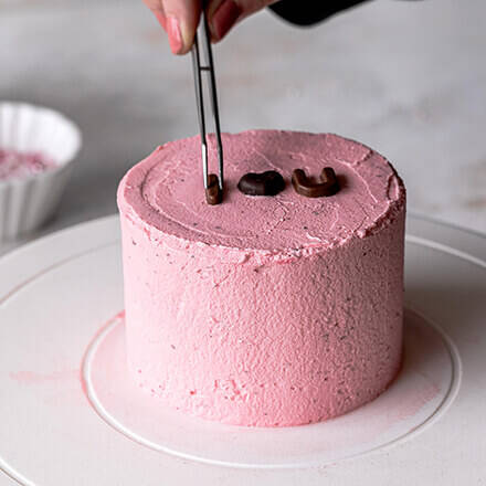 Torte wird mit Schokobuchstaben dekoriert