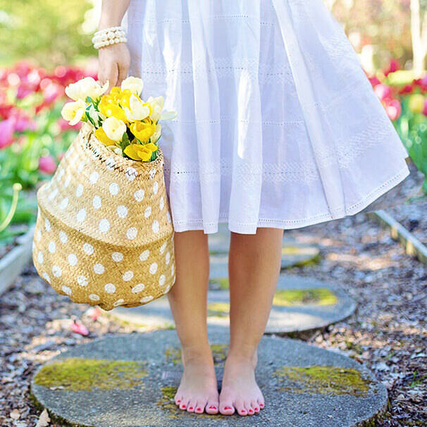 Ein Garten im Frühling. Eine Frau steht mit einem Korb, mit Tulpen drinnen im Garten.