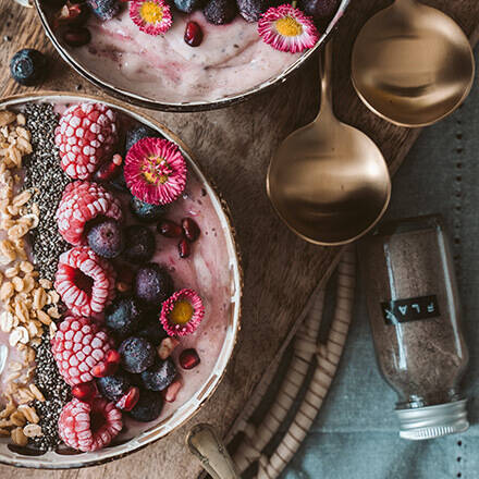 Frühstücksbowl in rosa mit Himbeeren und Walnüssen