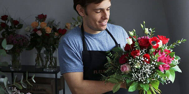 Florist, der einen Strauß in Rot-Pink bindet