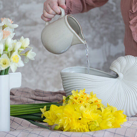 Eine bauchige Vase wird mit Wasser befüllt