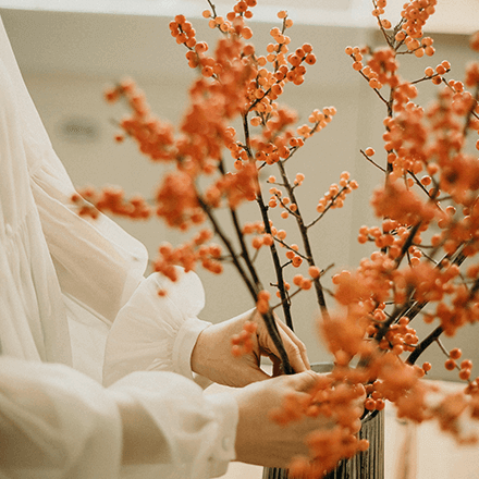 Eine Frau arrangiert Winterbeerensträucher in einer Vase