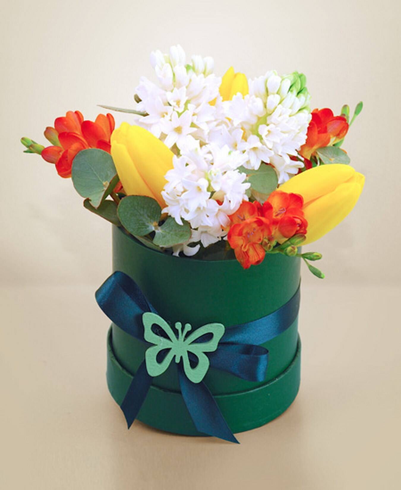 Blumenarrangement, Bouquet, gelbe Tulpen, weiße Blumen, grüne Geschenkbox, Blumenarrangement, Bouquet, runde Geschenkschachtel, grüner Karton, blaues Band