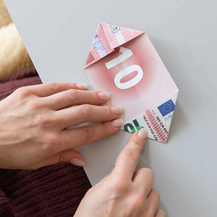 Die Ecken eines 10-Euro-Scheins werden eingefaltet