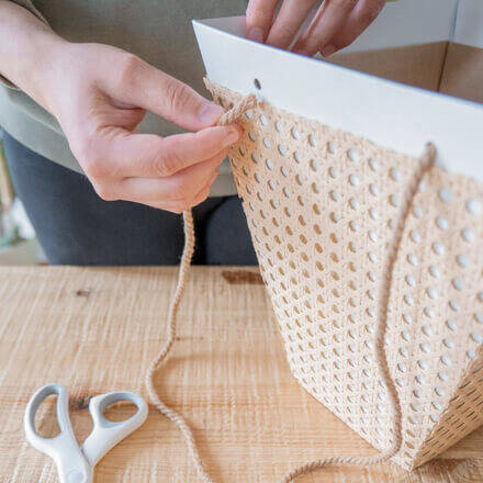 Der Flower-Bag wird bei einer Upcycling-Idee zu einer Geschenkbox mit Wiener Geflecht die Henkel in Form von Baumwollschnur in Naturfarben wieder angebracht.